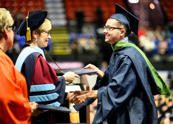 在2022年毕业典礼上，一名毕业生从劳拉·卡萨门托校长手中接过毕业证书.