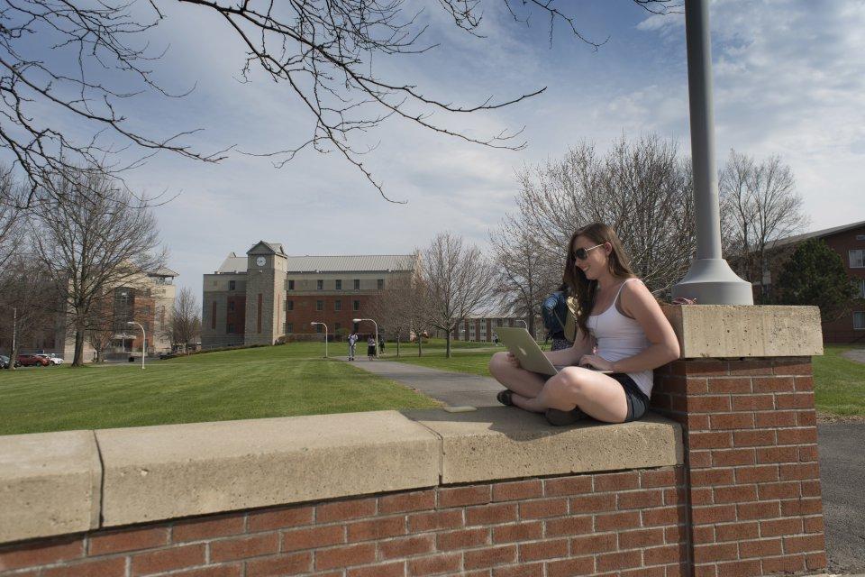 Student sitting on campus wall in Spring 060